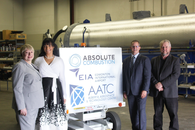 Laura Kilcrease, CEO of Alberta Innovates, Koleya Karringten, CEO of Absolute Combustion International, Steve Maybee, VP of Operations and Infrastructure, Edmonton International Airport and Rollie Dykstra, VP of Investments, Alberta Innovates, pose in front of the new Absolute Combustion International-SM1000 portable aircraft heater, tested and produced in Alberta.