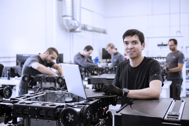 A photo of Attabotics employees working, with one smiling at the camera.